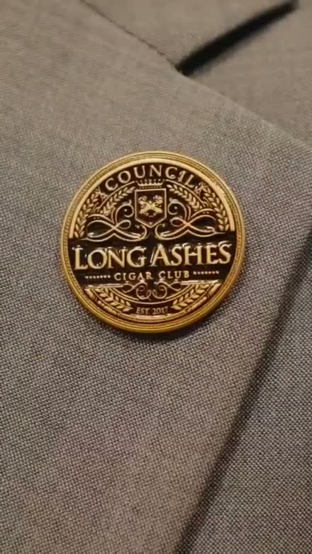 The genuine gold Long Ashes club lapel pin on a member's suit